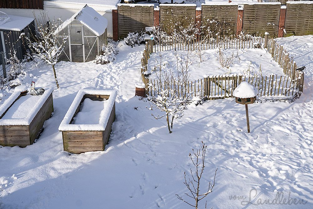 Blick von der Loggia auf unseren tief verschneiten Garten mit Gewächshaus, Hochbeeten und Bauerngarten